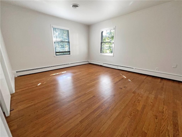 unfurnished room featuring wood-type flooring and baseboard heating