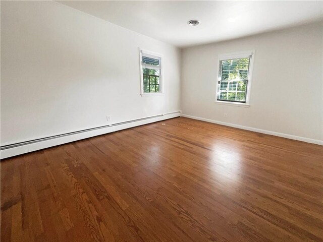 empty room featuring dark wood-type flooring and baseboard heating