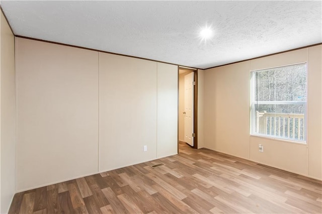 unfurnished bedroom with crown molding, a closet, light hardwood / wood-style floors, and a textured ceiling