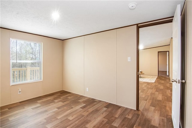 empty room featuring hardwood / wood-style flooring, crown molding, and a textured ceiling