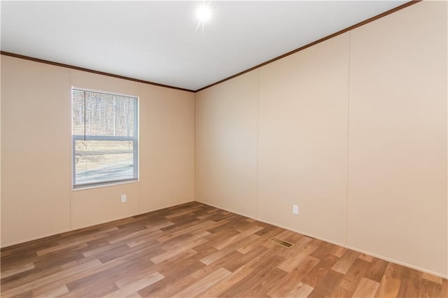 empty room featuring ornamental molding and hardwood / wood-style floors