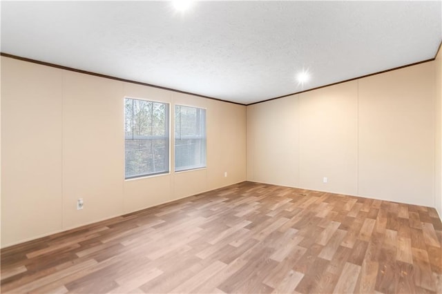 spare room featuring ornamental molding and light hardwood / wood-style floors