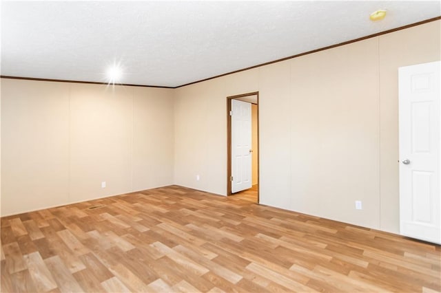 empty room with crown molding and light wood-type flooring