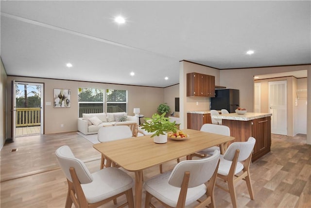 dining space with ornamental molding and light hardwood / wood-style floors