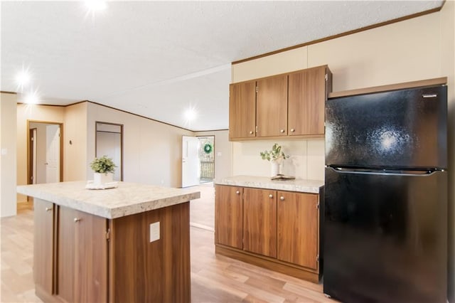 kitchen with a kitchen island, black fridge, and light hardwood / wood-style floors