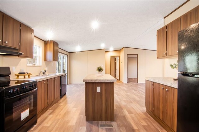 kitchen featuring sink, black appliances, a center island, and light wood-type flooring