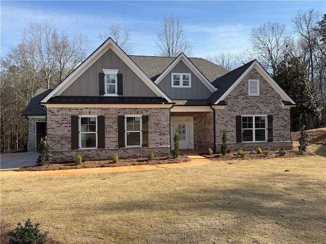 craftsman-style house with board and batten siding, a front yard, brick siding, and roof with shingles