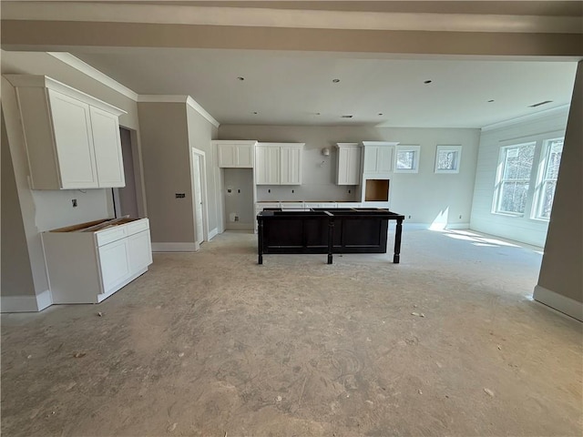 kitchen featuring a center island, white cabinetry, crown molding, and baseboards