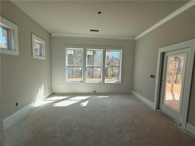 empty room with crown molding, concrete floors, and baseboards