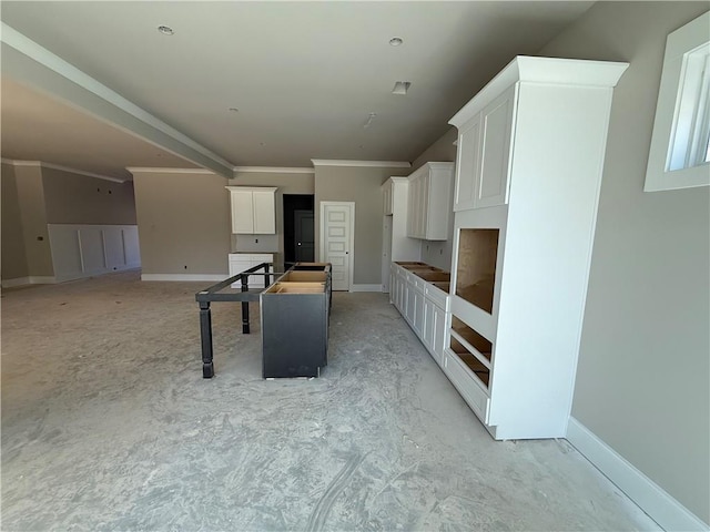 kitchen featuring baseboards, a kitchen island, white cabinetry, and crown molding