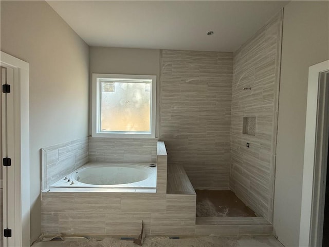 bathroom with a tile shower and a bath