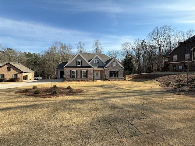 craftsman house featuring driveway, stone siding, and board and batten siding