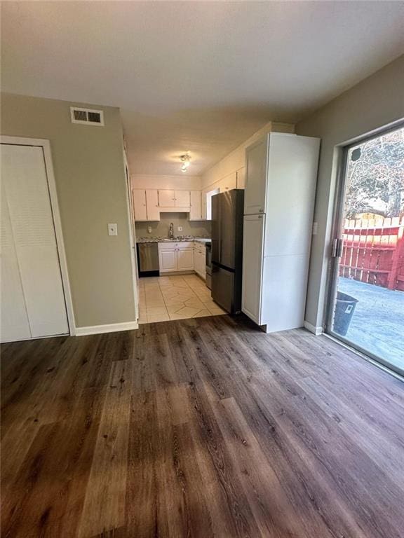 4701 Flat Shoals Rd, Union City, GA 30291 - kitchen with freestanding refrigerator, light wood-type flooring, white cabinetry, dishwashing machine, and light countertops
