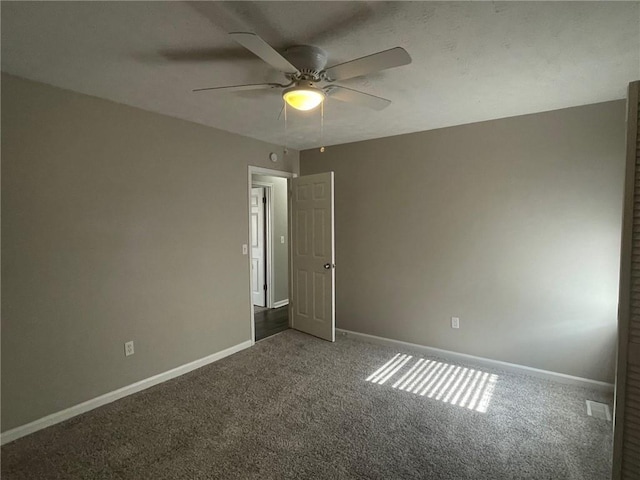 carpeted spare room featuring ceiling fan and baseboards