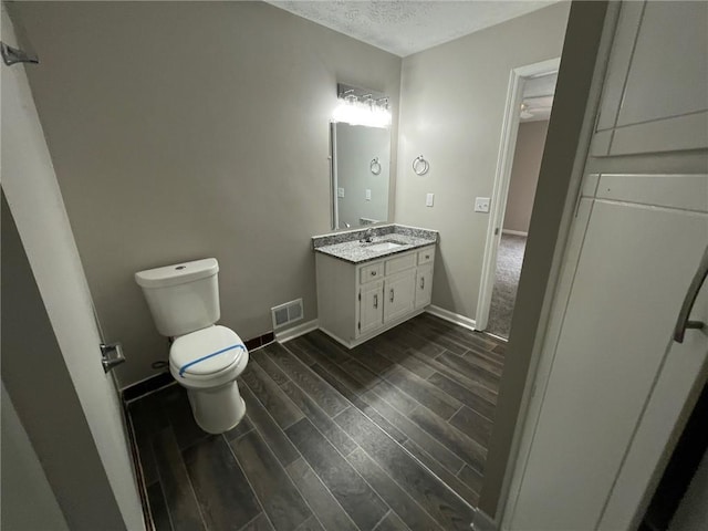 bathroom with visible vents, baseboards, toilet, wood tiled floor, and vanity