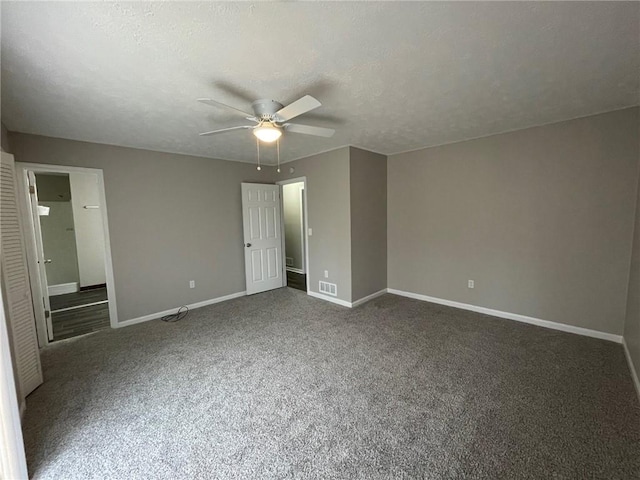 unfurnished bedroom featuring a textured ceiling, dark colored carpet, visible vents, and baseboards