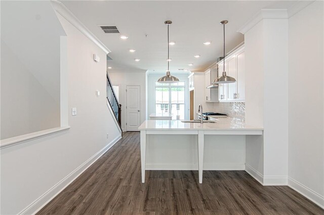 kitchen featuring a kitchen breakfast bar, dark wood-type flooring, kitchen peninsula, and pendant lighting