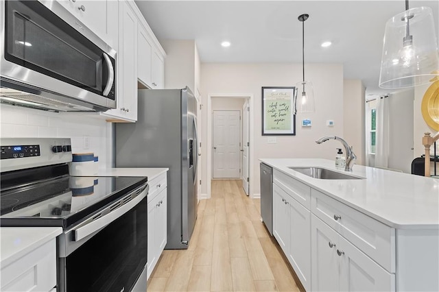 kitchen featuring stainless steel appliances, light countertops, a sink, and white cabinetry