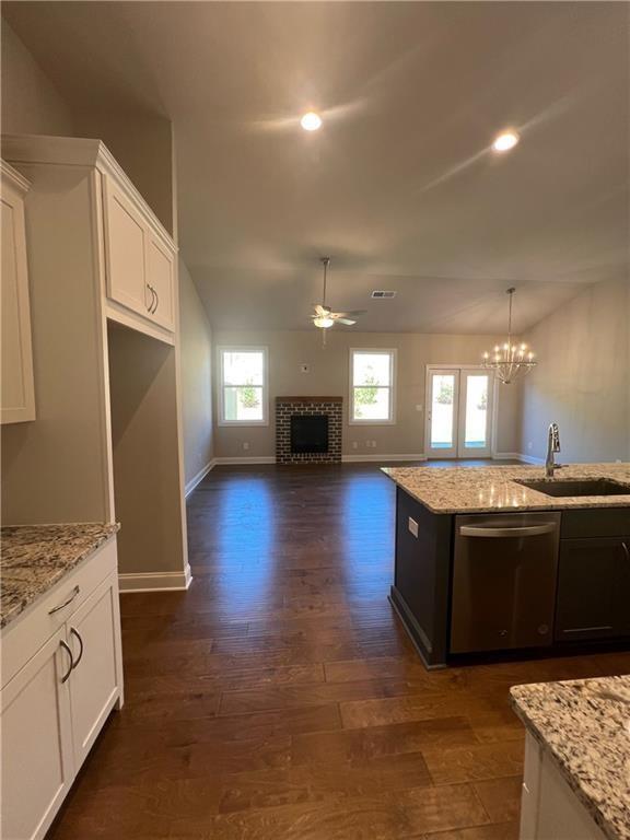 kitchen featuring white cabinetry, dishwasher, sink, and light stone counters