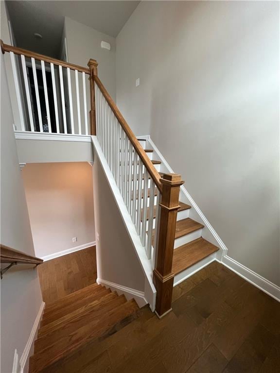 stairs with hardwood / wood-style flooring and a high ceiling