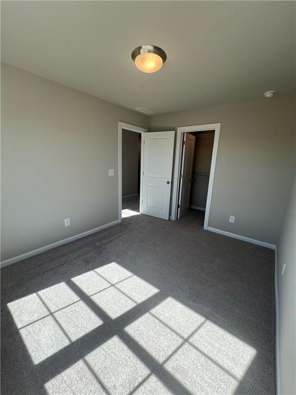 unfurnished bedroom featuring a walk in closet, carpet floors, and a closet