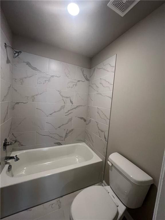 bathroom with tiled shower / bath combo and toilet