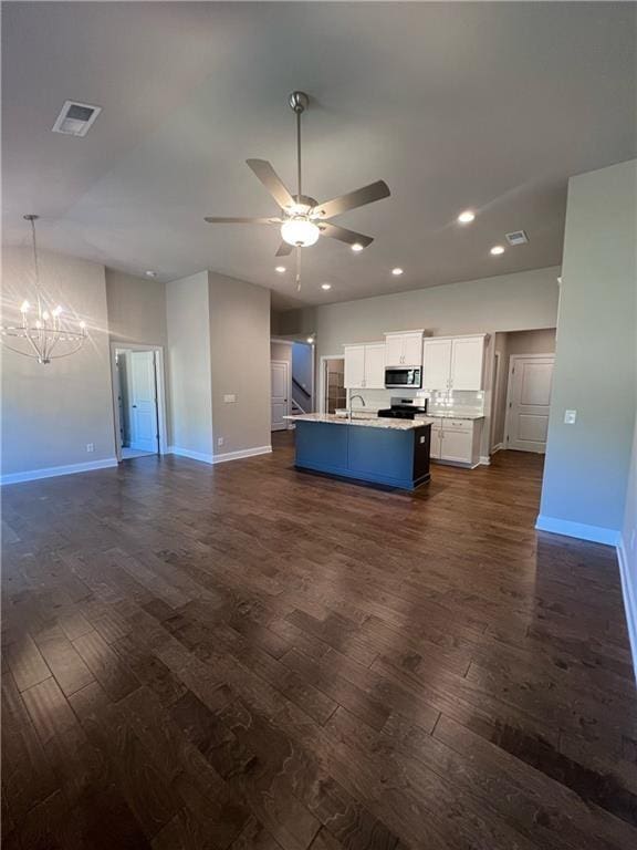 kitchen with stainless steel appliances, white cabinets, a center island with sink, dark hardwood / wood-style flooring, and ceiling fan with notable chandelier