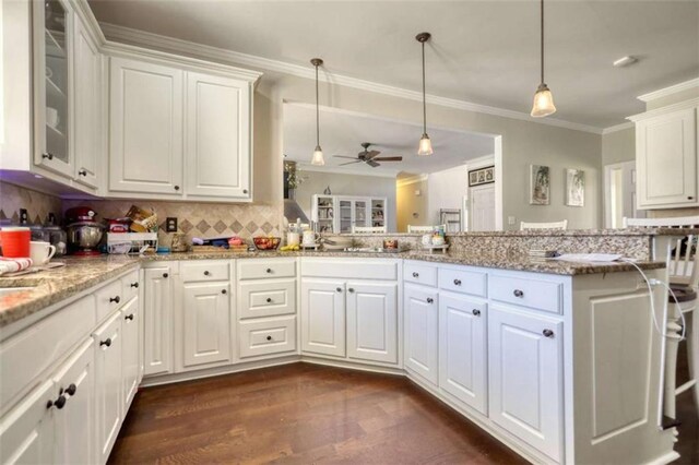 kitchen with backsplash, dark wood-style floors, white cabinets, ceiling fan, and ornamental molding