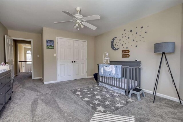 carpeted bedroom with a nursery area, baseboards, a closet, and a ceiling fan