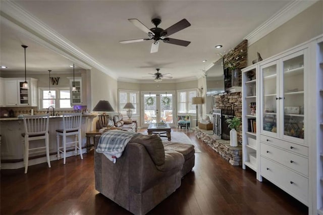 living area with a ceiling fan, dark wood-style flooring, ornamental molding, and a fireplace