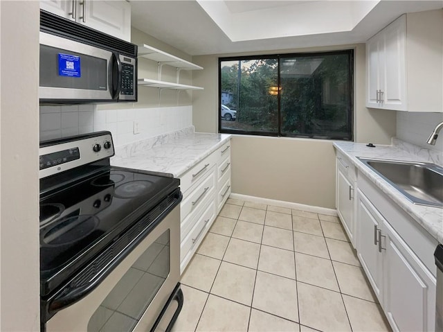 kitchen featuring tasteful backsplash, white cabinets, a sink, and electric range