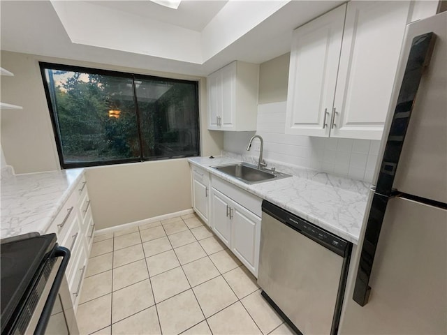 kitchen featuring light tile patterned floors, a sink, white cabinetry, appliances with stainless steel finishes, and backsplash