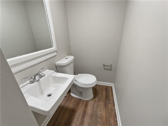 bathroom with toilet, baseboards, a sink, and wood finished floors