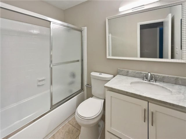 bathroom featuring toilet, shower / bath combination with glass door, tile patterned flooring, and vanity