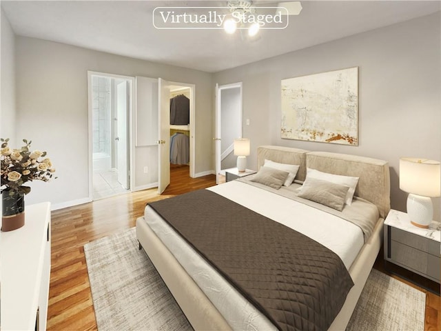 bedroom featuring a walk in closet, ensuite bathroom, baseboards, and wood finished floors