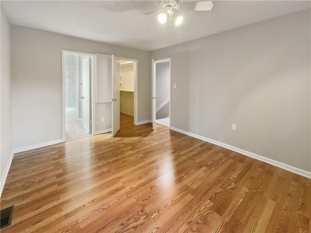 unfurnished bedroom featuring light wood-type flooring, visible vents, a spacious closet, and baseboards