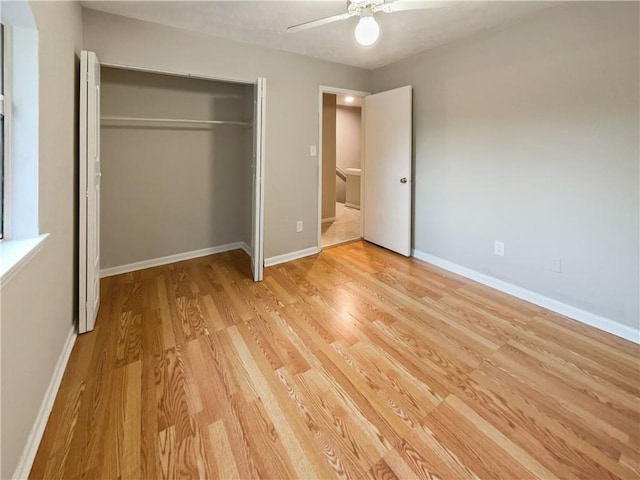 unfurnished bedroom with light wood-type flooring, ceiling fan, baseboards, and a closet