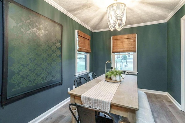 dining room with ornamental molding, wood-type flooring, a textured ceiling, and a chandelier