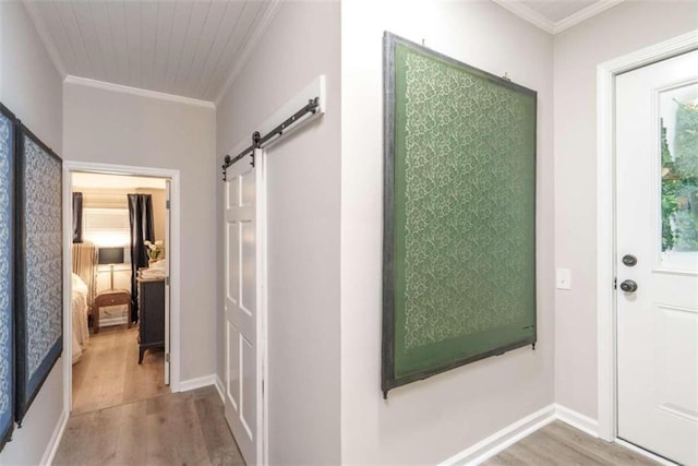 corridor featuring a barn door, crown molding, and light hardwood / wood-style flooring