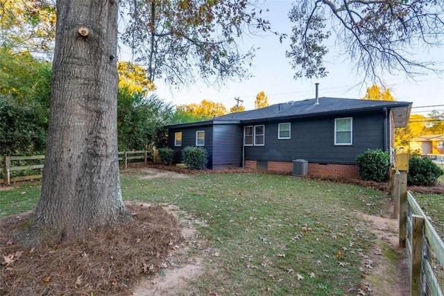 back of property with central air condition unit and a lawn