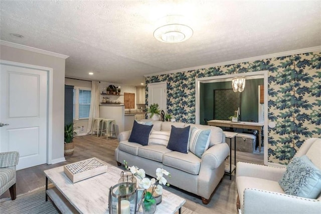 living room featuring crown molding, wood-type flooring, a textured ceiling, and a chandelier