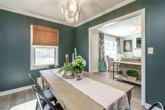 dining space with hardwood / wood-style floors, crown molding, and a notable chandelier