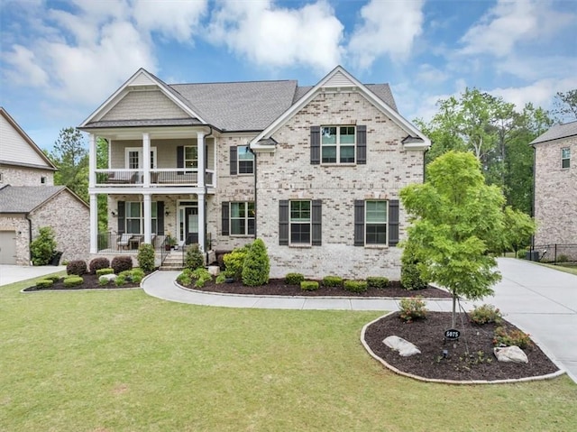 view of front of home featuring a porch, brick siding, a balcony, a front lawn, and concrete driveway