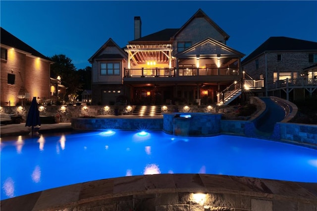 pool at night featuring an in ground hot tub