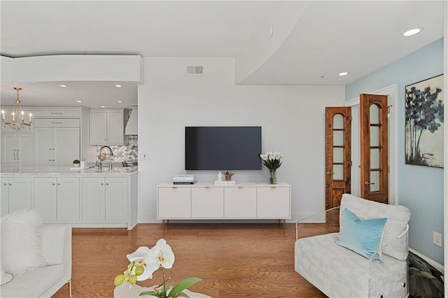 living room featuring a chandelier, recessed lighting, baseboards, wood finished floors, and visible vents