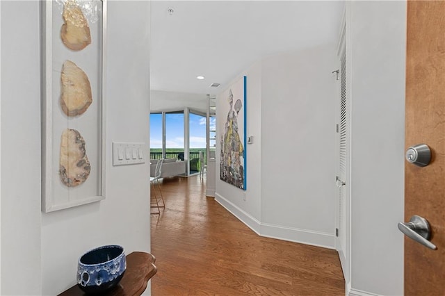 hall with baseboards, recessed lighting, floor to ceiling windows, and wood finished floors