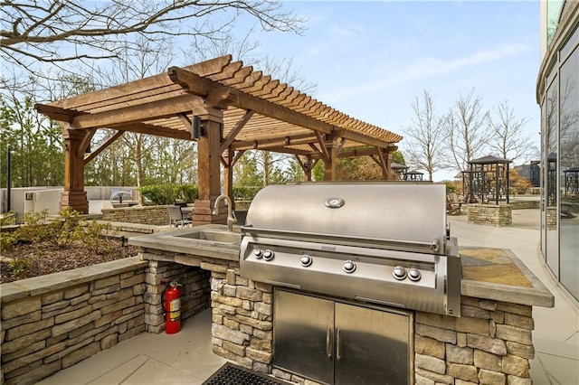 view of patio / terrace with a sink, a pergola, a grill, and exterior kitchen