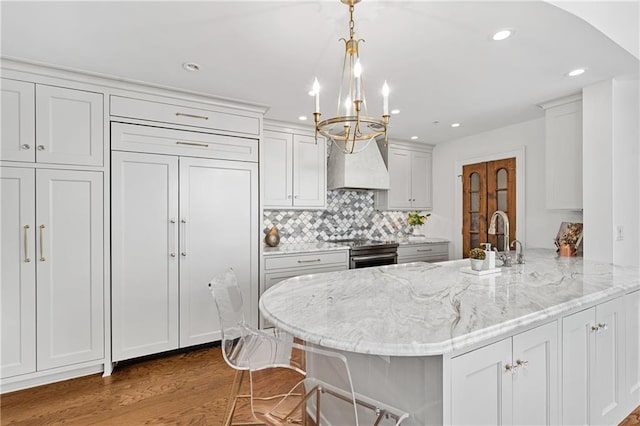 kitchen featuring stainless steel electric range, a sink, a peninsula, a chandelier, and custom range hood