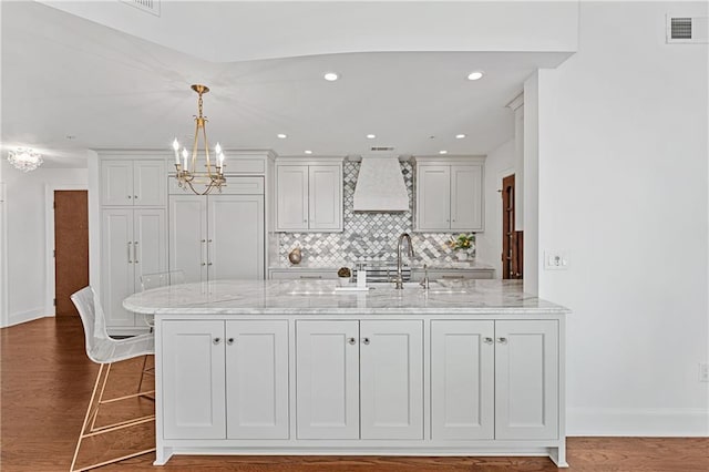 kitchen featuring visible vents, custom exhaust hood, light stone countertops, dark wood-type flooring, and a sink