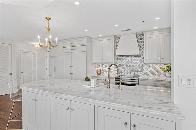 kitchen featuring backsplash, visible vents, pendant lighting, custom exhaust hood, and an inviting chandelier
